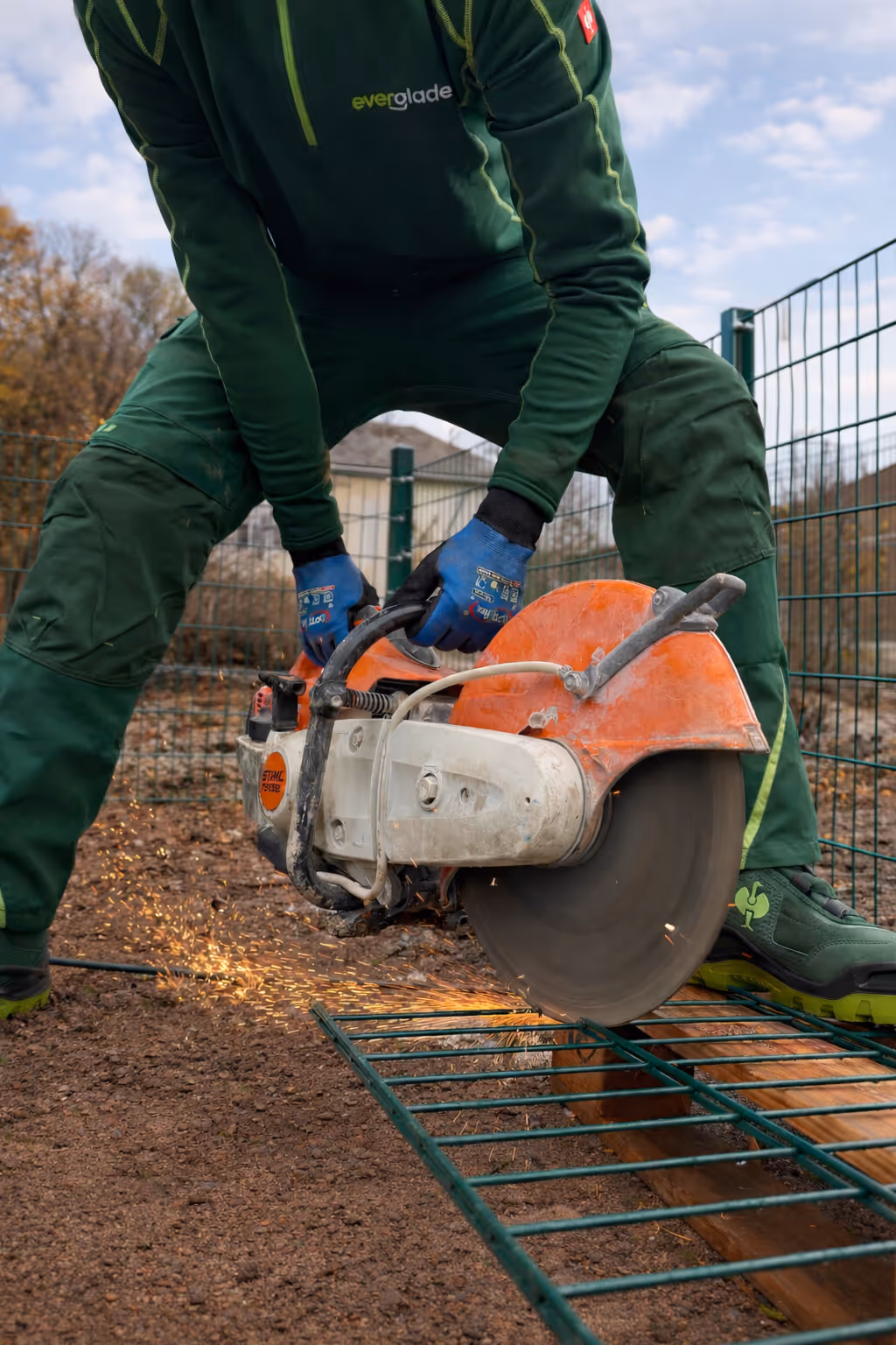Mitarbeiter der Everglade GmbH trennt beim Zaunbau einen Stein mit dem Trennschleifer