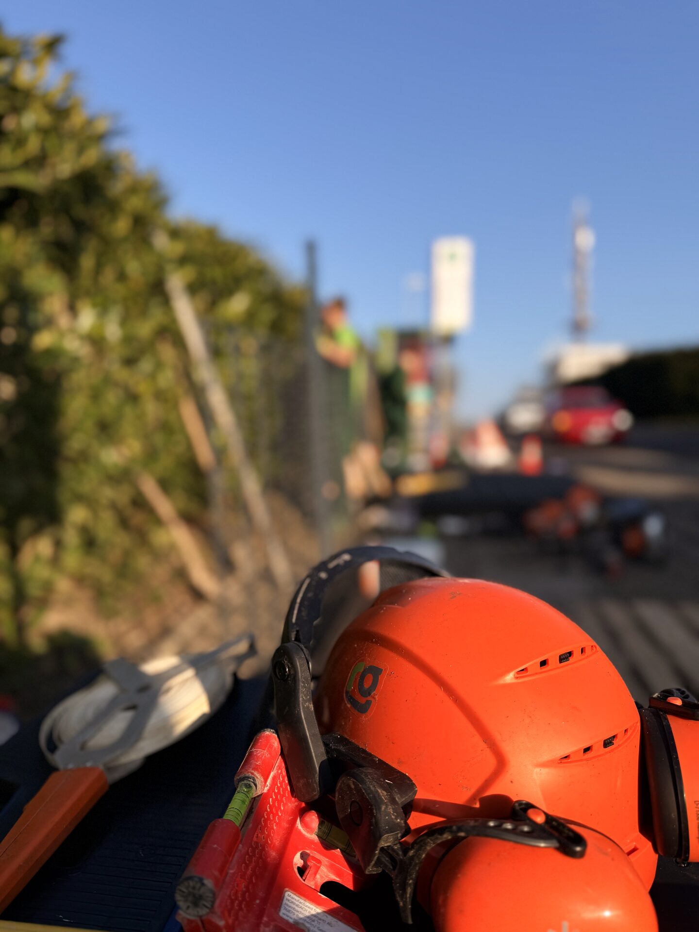 Orangefarbener Schutzhelm mit Everglade-Logo vor einer abgesicherten Baustelle an einer Straße