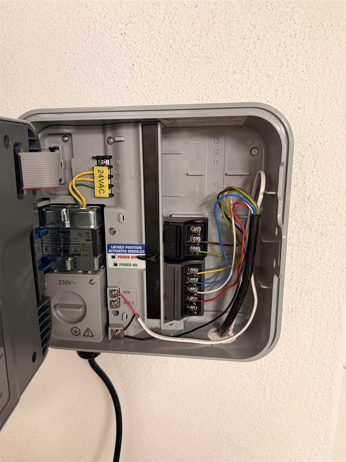 Geöffnetes Steuergerät einer Bewässerungsanlage an einer Hauswand