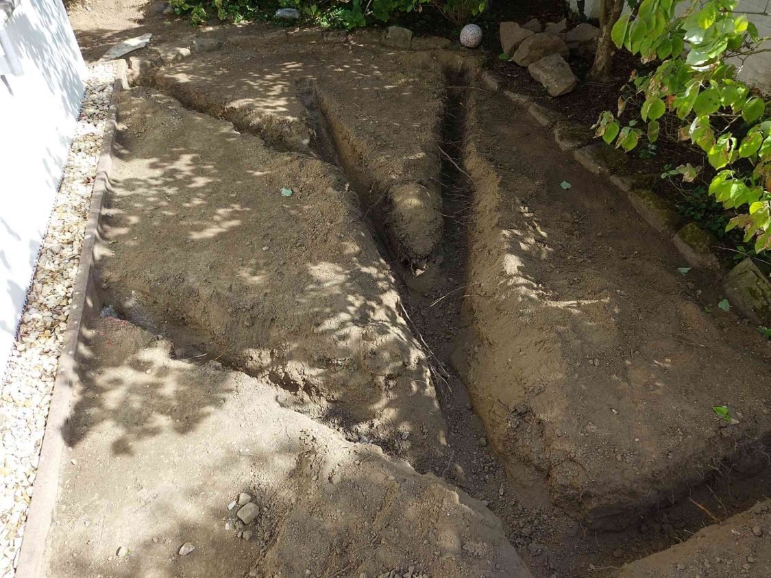 Frisch gezogene Leitungsgräben, die sich im Garten verzweigen