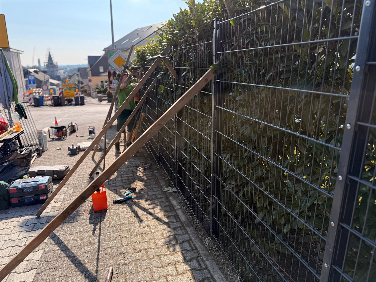 Lange Reihe abgestützter Zaunfelder am Gehweg, im Hintergrund die Straße