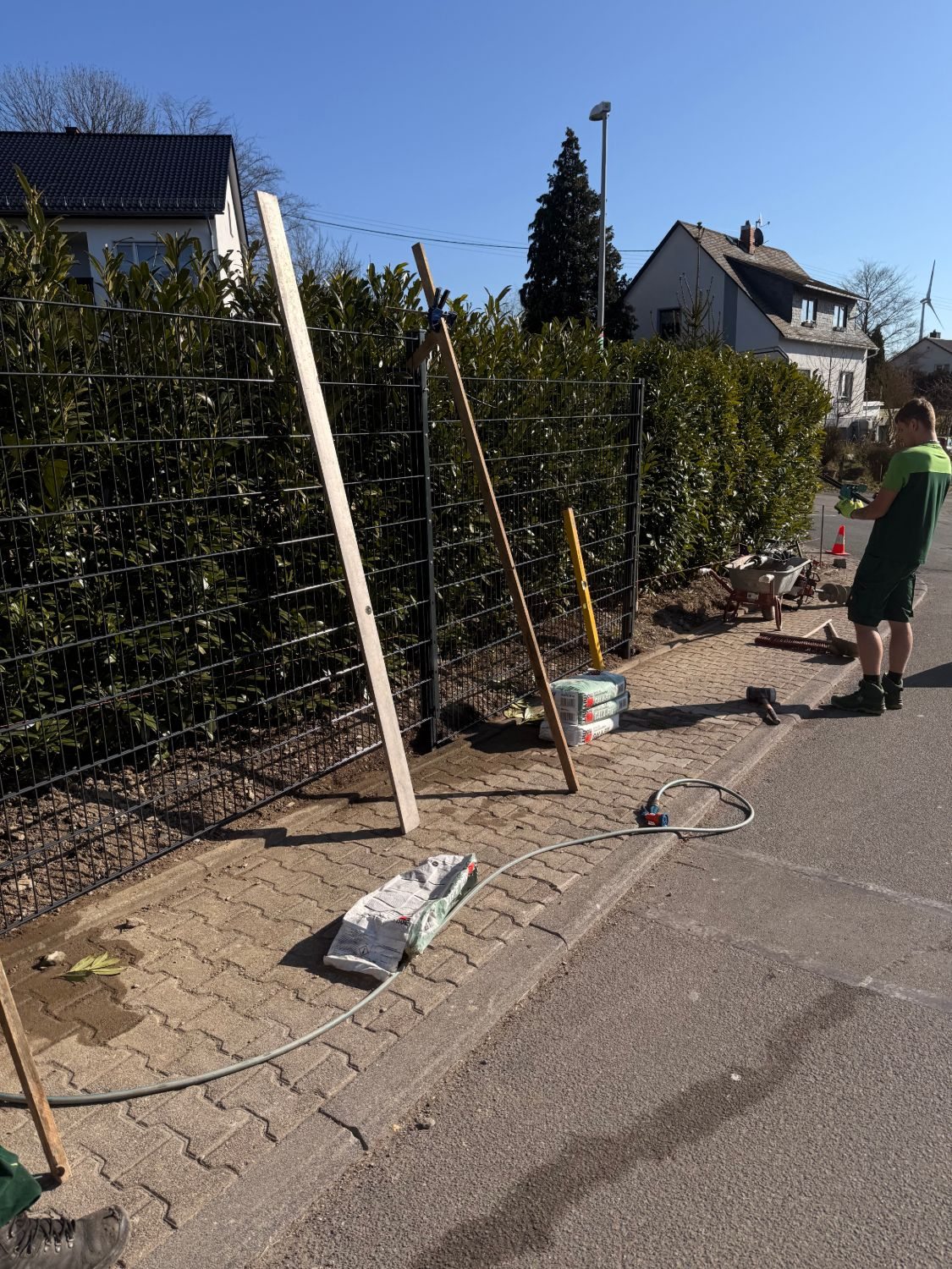 Neu gesetzte Zaunfelder mit Holzlatten abgestützt, davor Säcke mit Schnellbeton