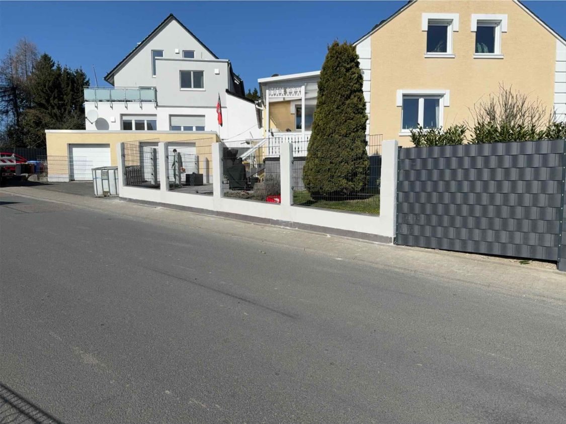Nachher: Zaunfelder zwischen den Pfeilern und daneben der hohe Zaun mit Sichtschutz an der Straße