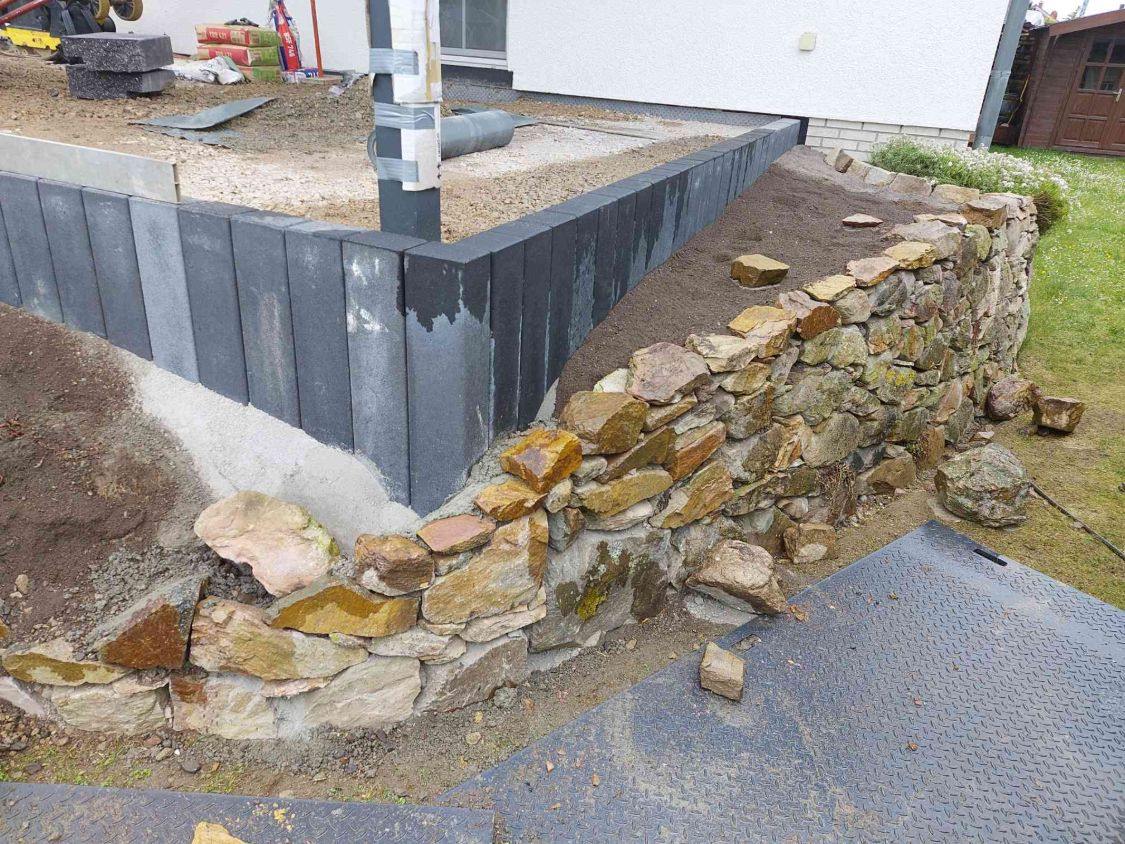 Neu aufgesetzte Trockenmauer aus Bruchstein vor den Palisaden