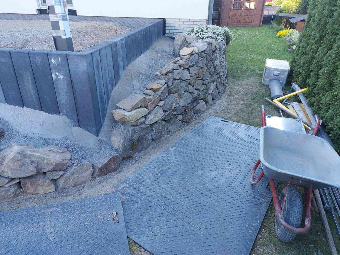 Ecke aus anthrazitfarbenen Palisaden und Trockenmauer