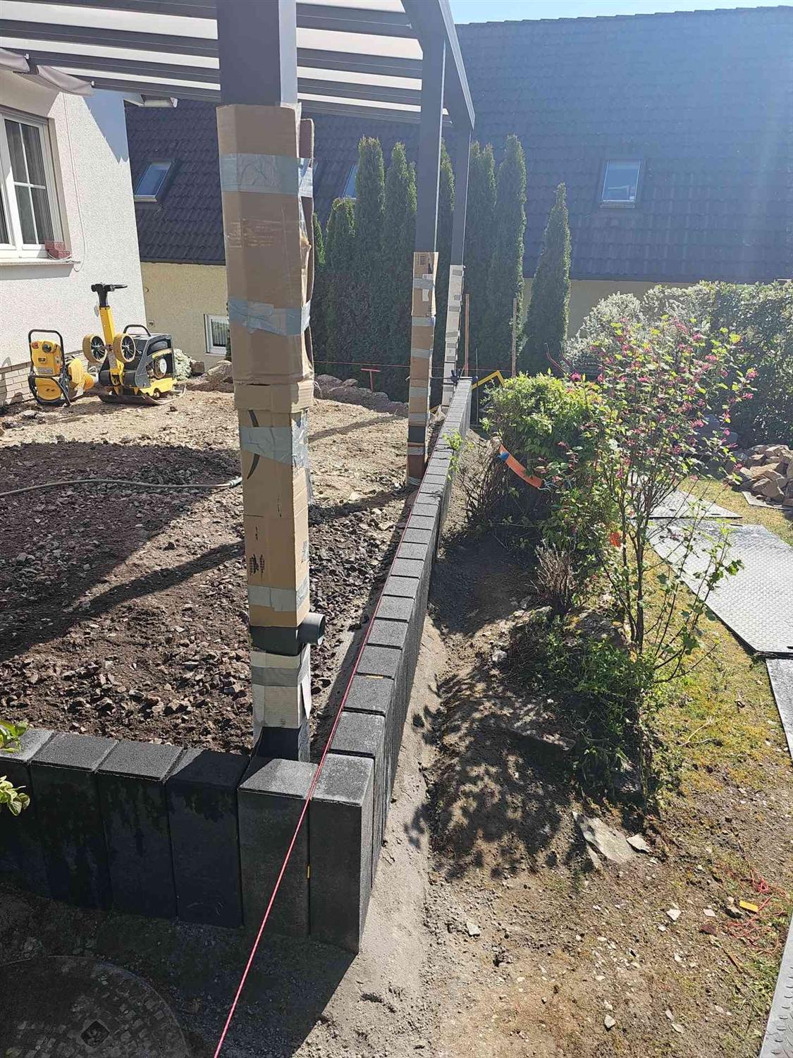 Palisadenreihe entlang einer gespannten roten Schnur, dahinter die Terrassenfläche