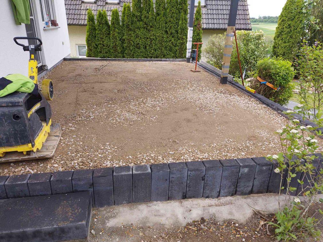 Verdichtete Tragschicht aus Schotter, eingefasst von Betonpalisaden, vorne die neue Blockstufe
