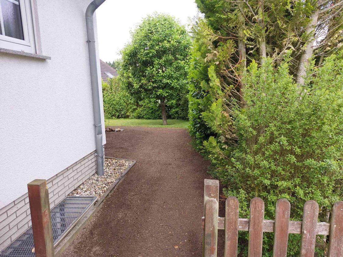 Frisch eingesäter Weg zwischen Hauswand und Hecke