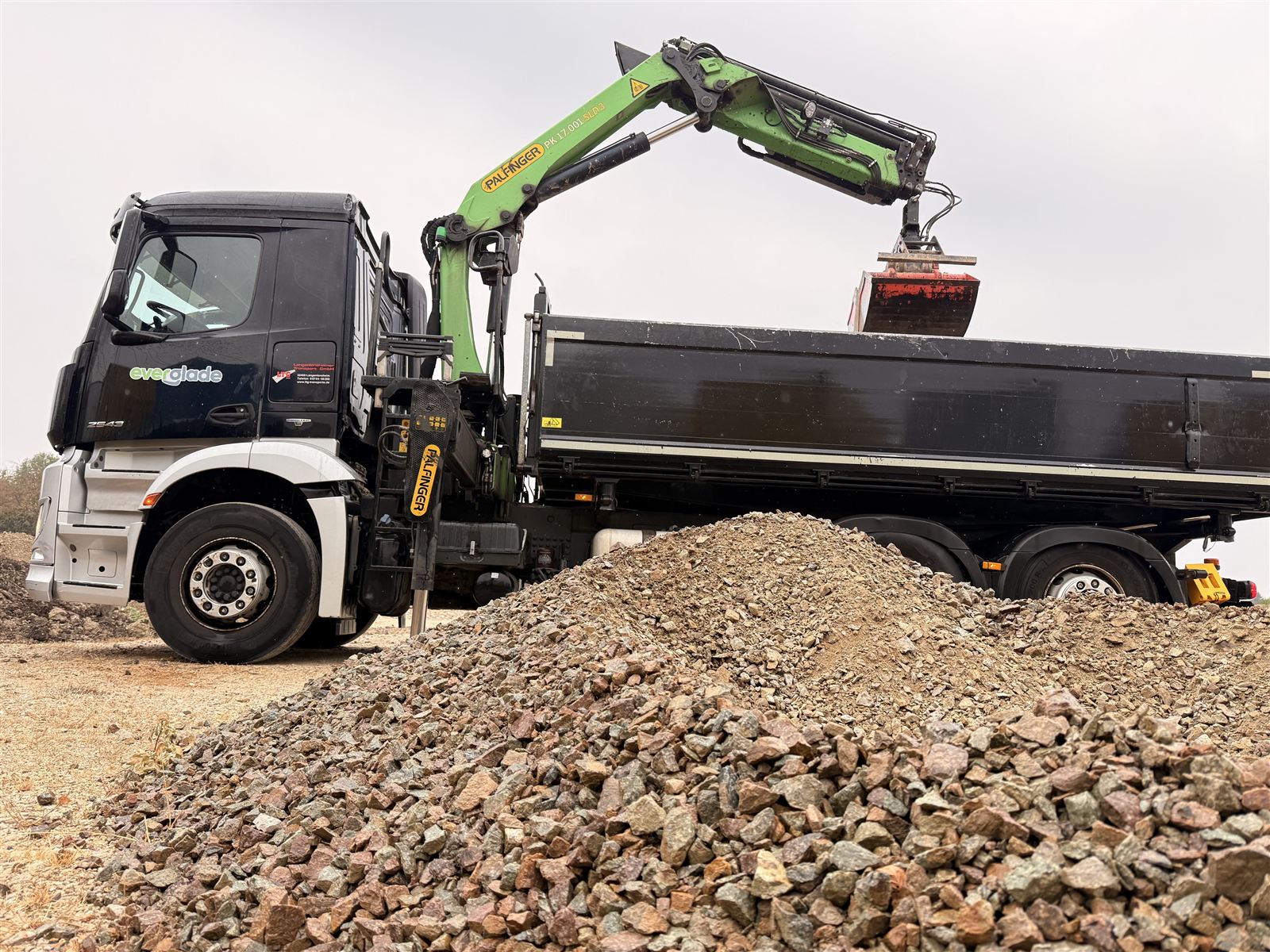 Kran-Lkw der Everglade GmbH mit Greifer an einem Haufen Schüttgut
