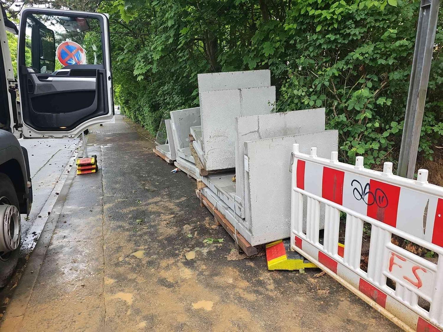 Winkelstützen aus Beton stehen auf Holzrahmen am Gehweg neben dem Lkw