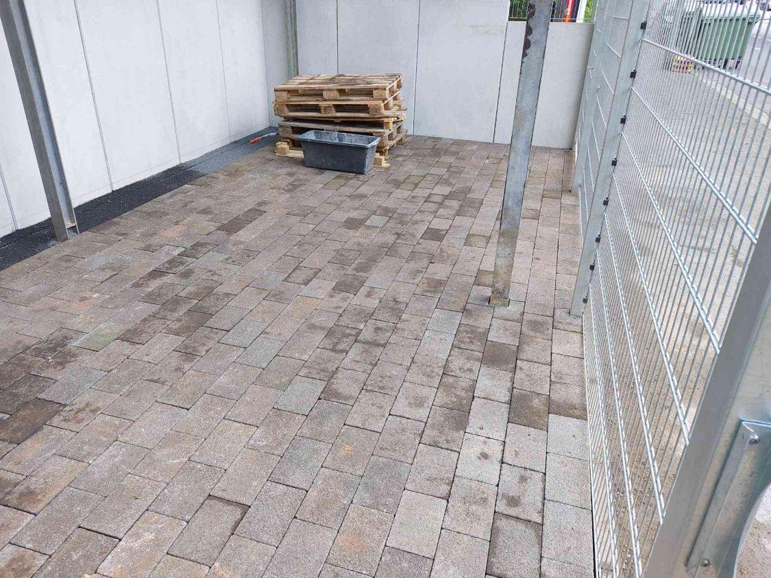 Neu verlegtes Rechteckpflaster zwischen Zaun und Sichtbetonwand