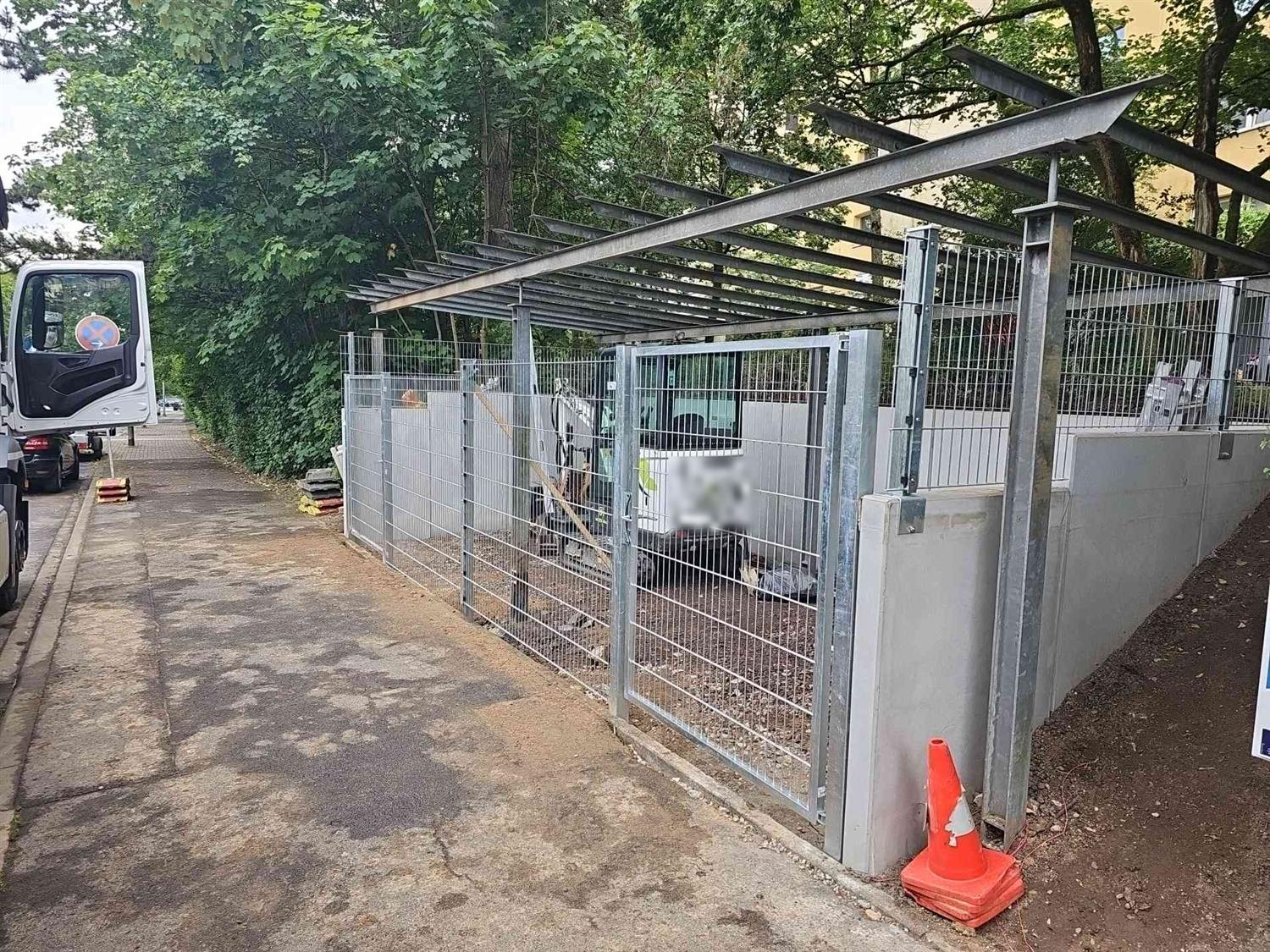 Neue verzinkte Tore und Zaun zur Straße, dahinter die Sichtbetonwände