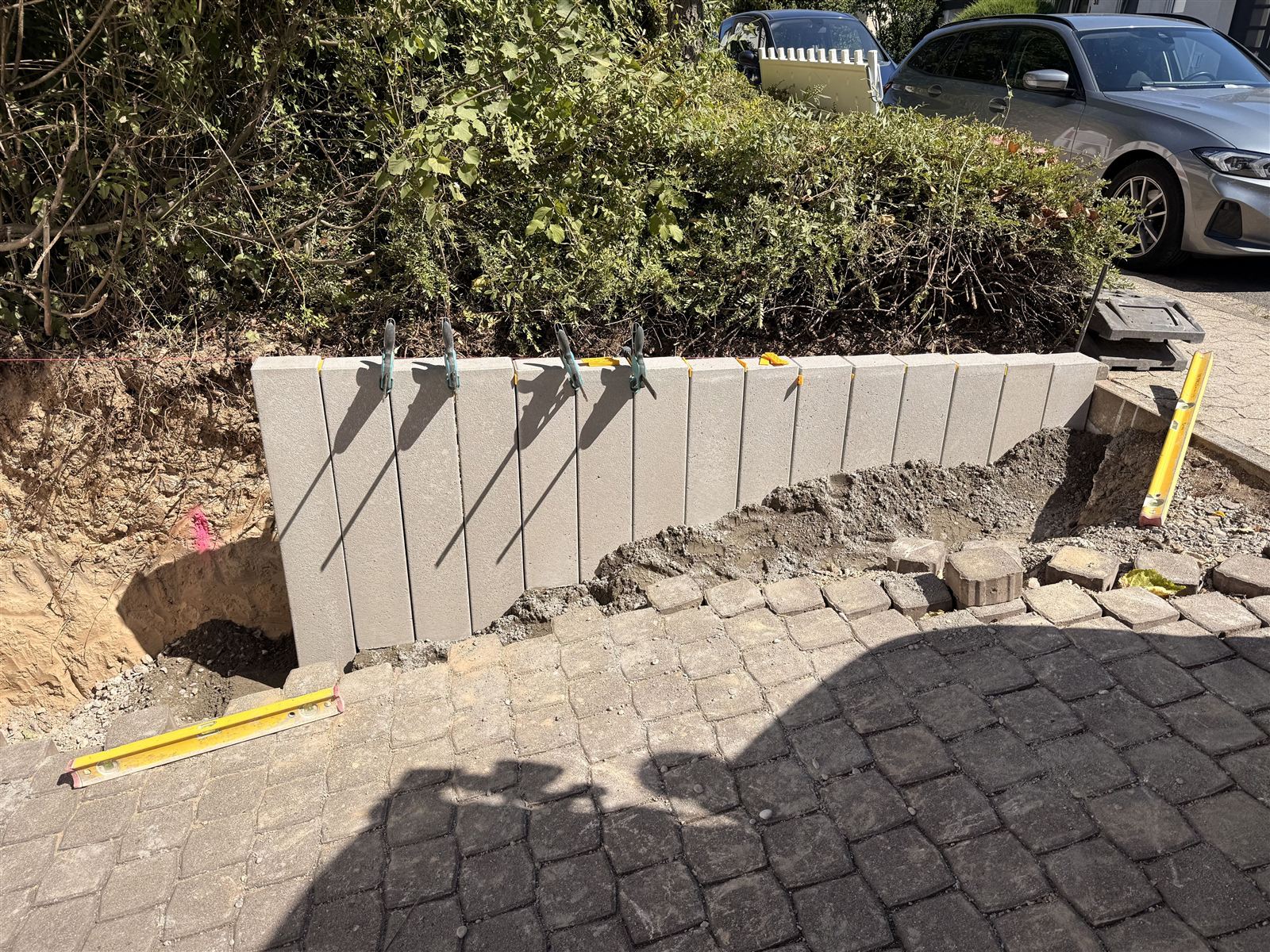 Neu gesetzte Betonpalisaden zwischen Pflasterfläche und Beet