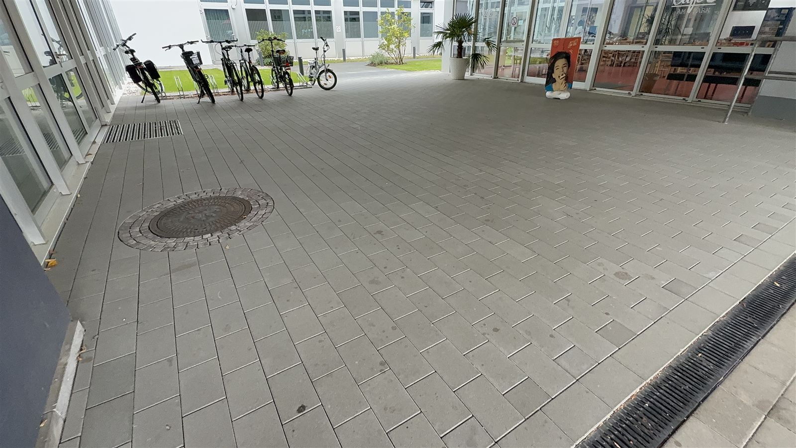 Neue Pflasterfläche vor einem Gebäudeeingang mit Entwässerungsrinne am Rand