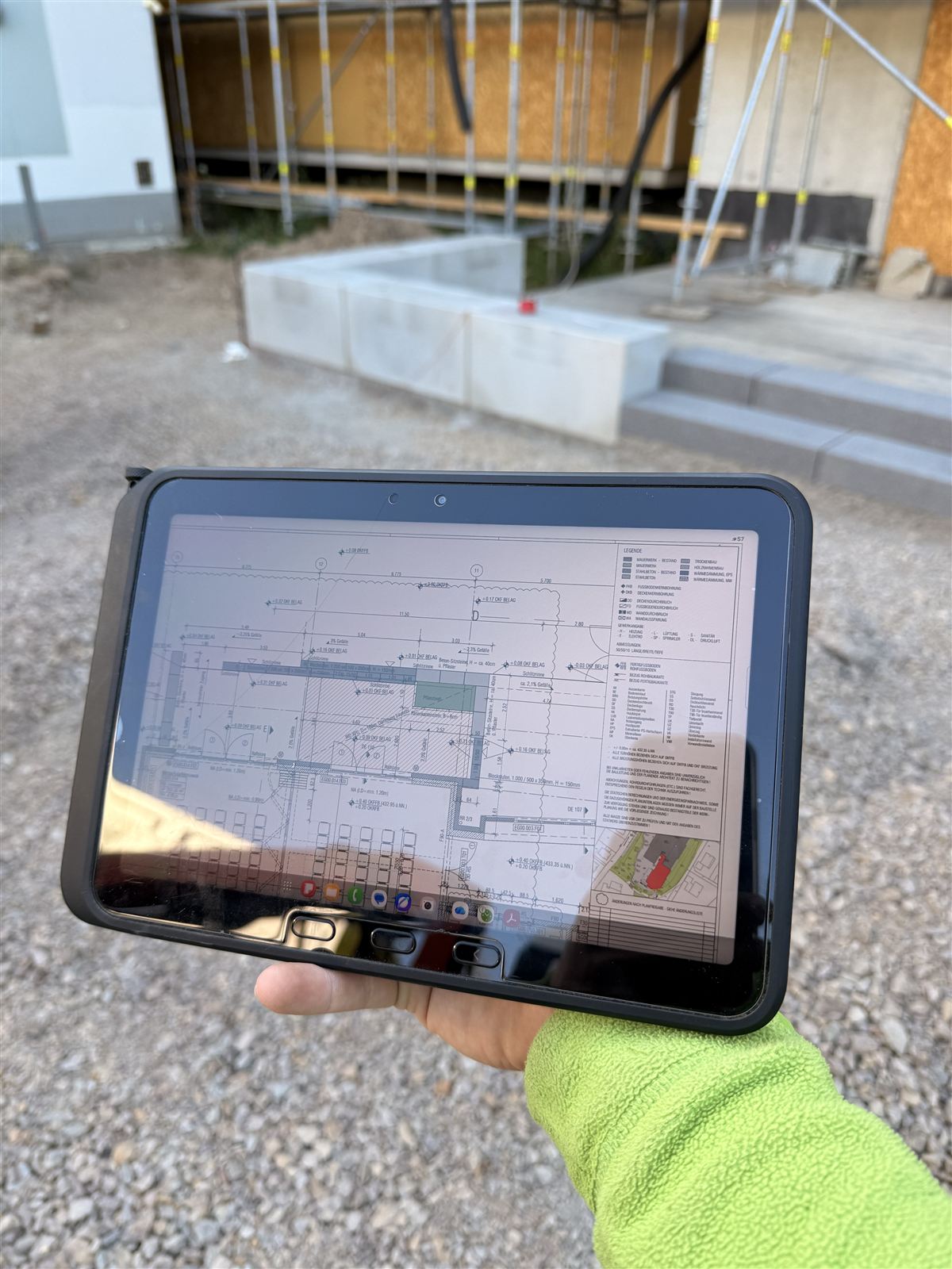 Mitarbeiter hält auf der Baustelle ein Tablet mit dem Ausführungsplan