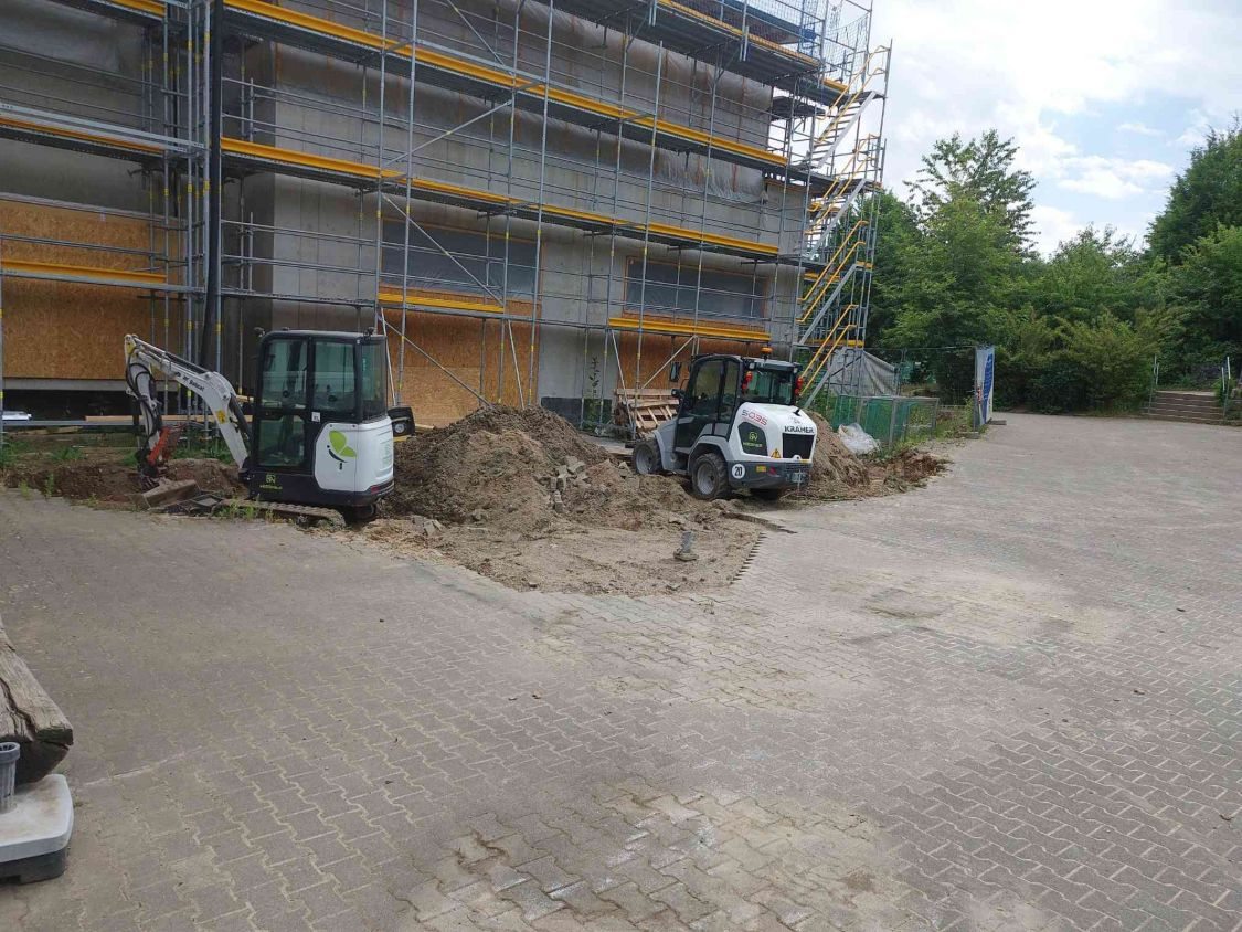 Minibagger und Radlader beim Aushub vor dem eingerüsteten Anbau