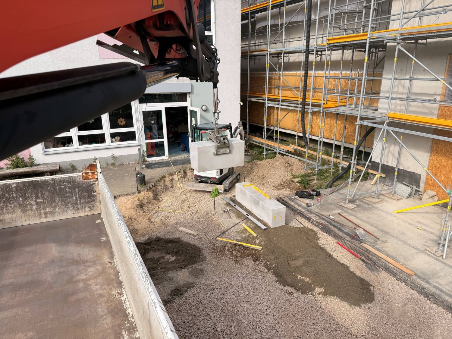 Der Ladekran hebt einen Sitzblock aus Beton an seinen Platz