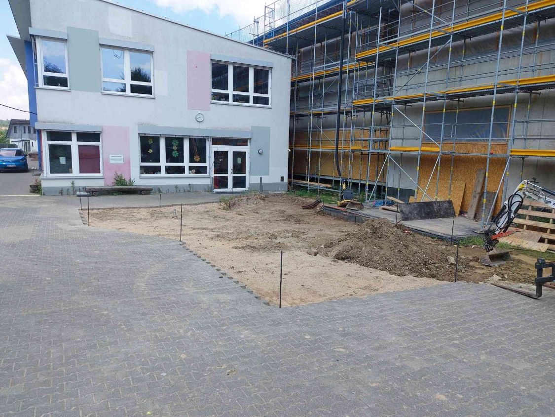Die Fläche vor der Schule ist aufgenommen und mit Stangen abgesteckt